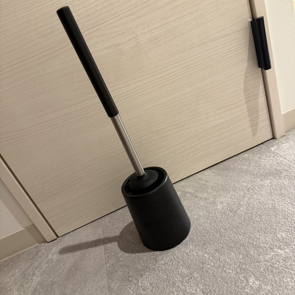 トイレの床に自立して置かれた、黒いトイレ掃除ブラシ