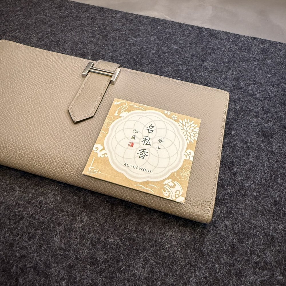 長財布の上に置かれた、名私香 伽羅のパッケージ。財布の幅の半分ほどの大きさ